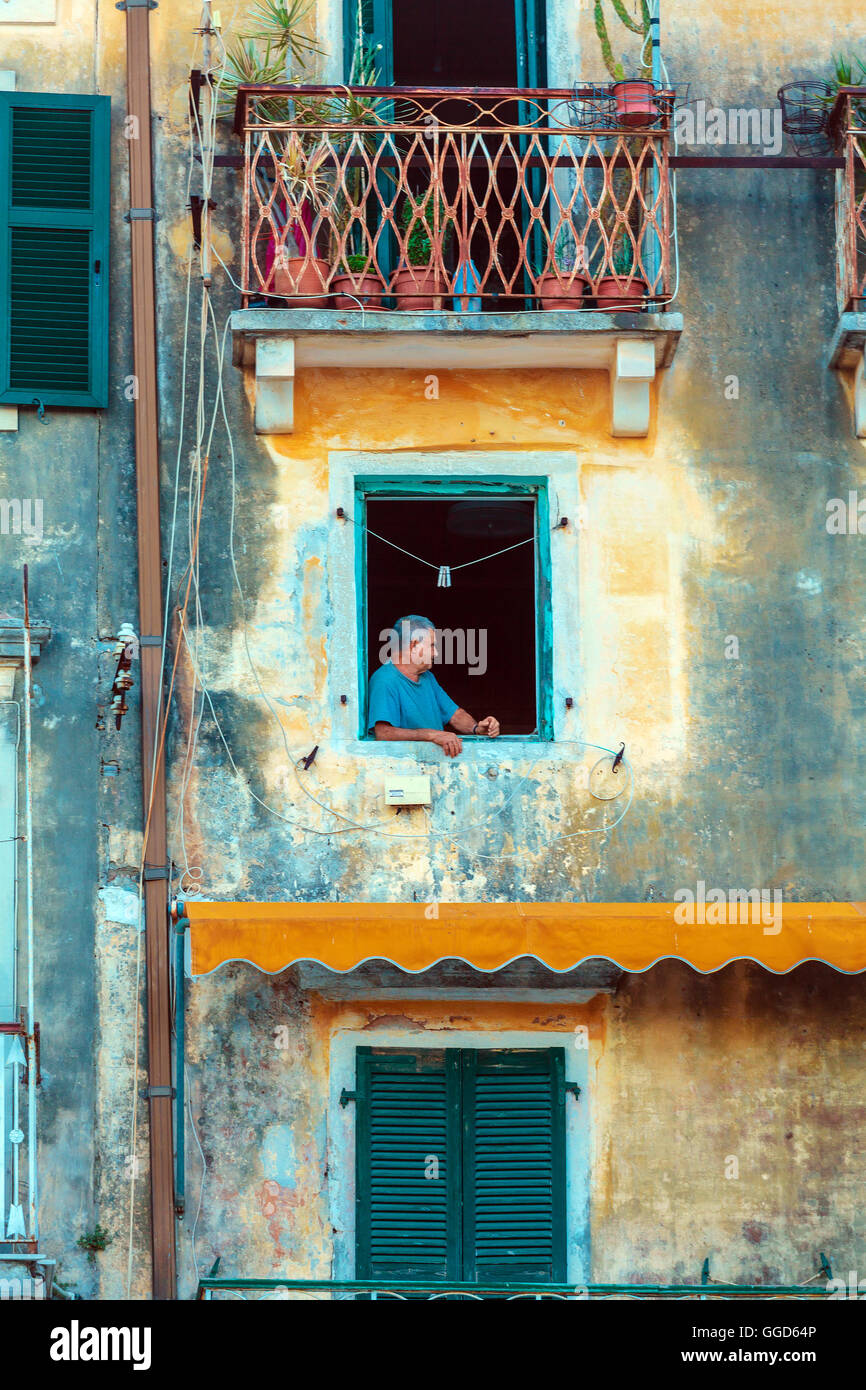Corfù, Grecia - luglio 6, 2011: uomo vecchio nella finestra di antica casa tipica Foto Stock