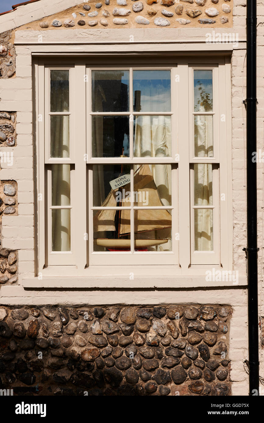 Crema leggera anta window set in pietra parete di ciottoli con una barca a vela nella finestra con etichetta dicendo andato in barca a vela Foto Stock