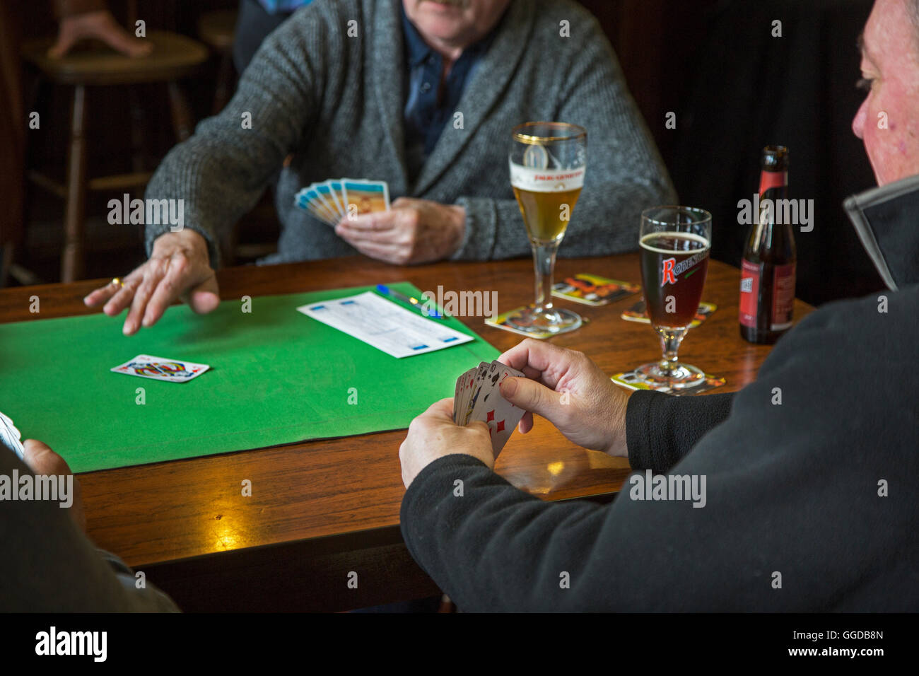 Scheda anziani giocatori che giocano le carte in tavola in pub Foto Stock