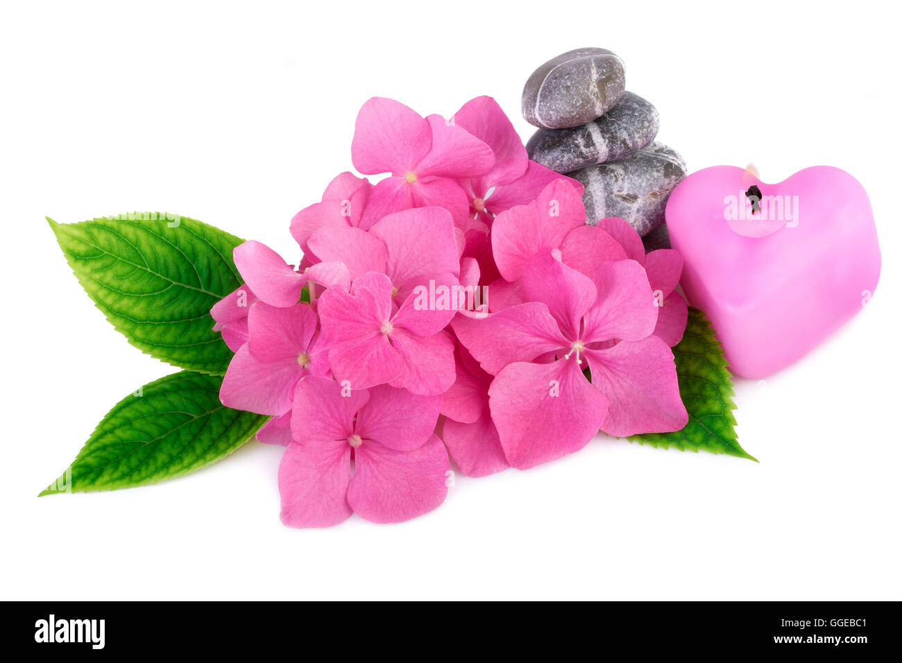 Pietre Spa zen con fiori e candela a forma di cuore, Foto Stock