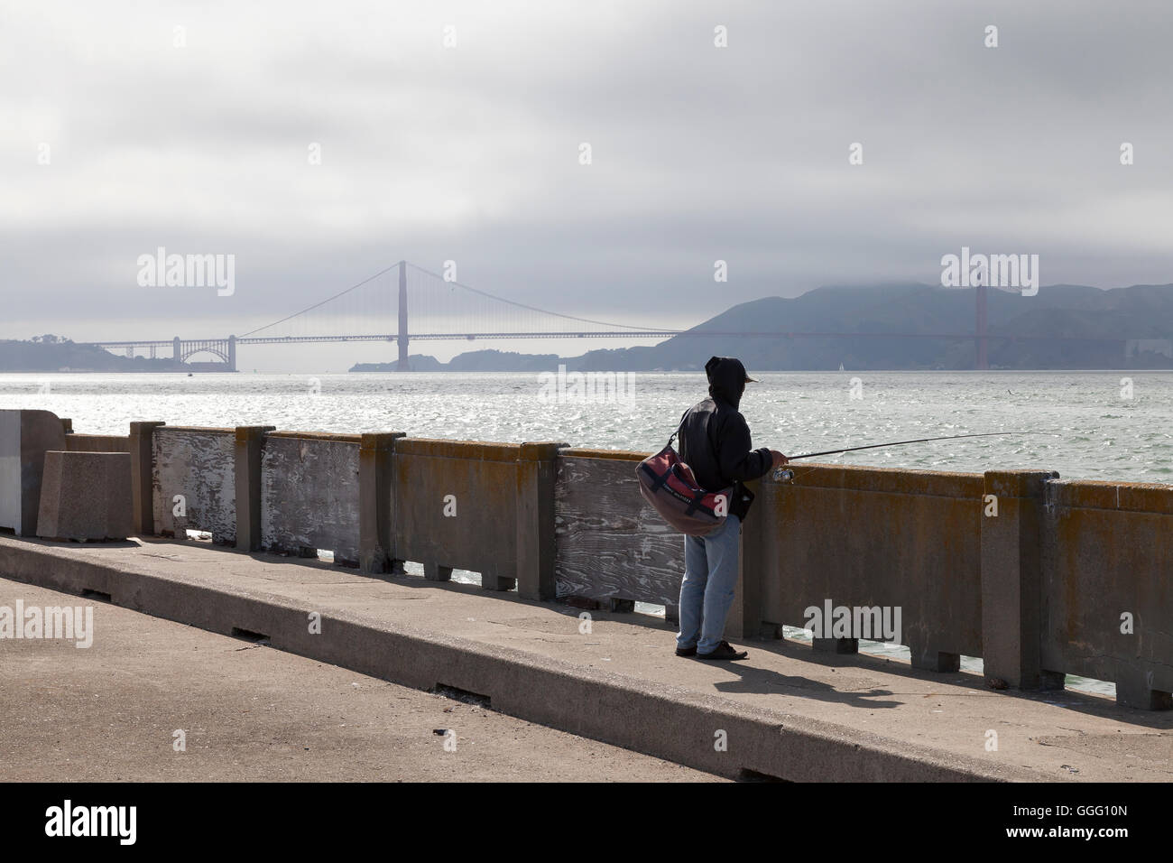 San Francisco, California: Uomo di pesca sul parco acquatico Pier in San Francisco Maritime National Historical Park. Foto Stock