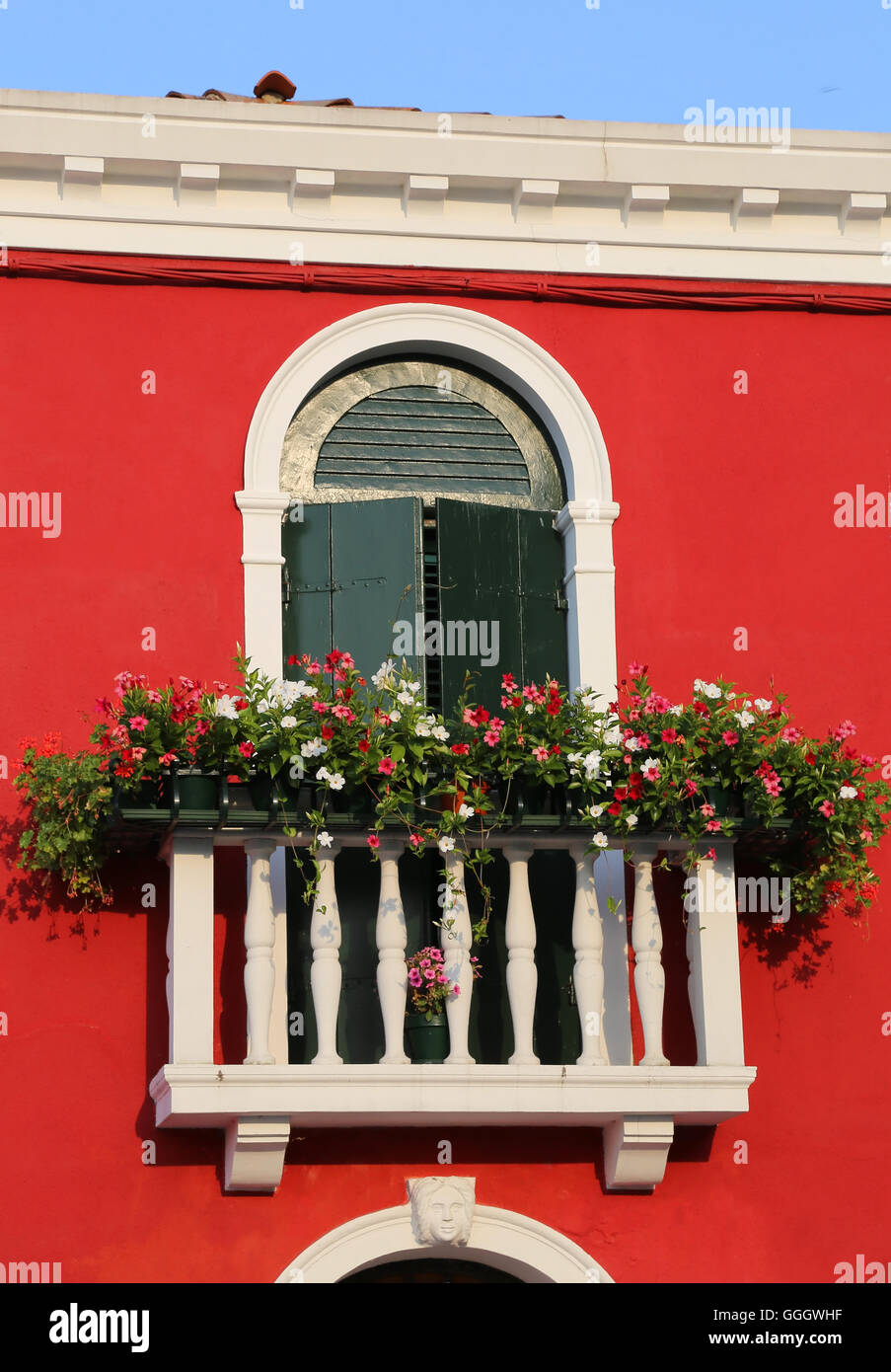 Bellissimo balcone fiorito con una finestra in casa e molti vasi di fiori Foto Stock