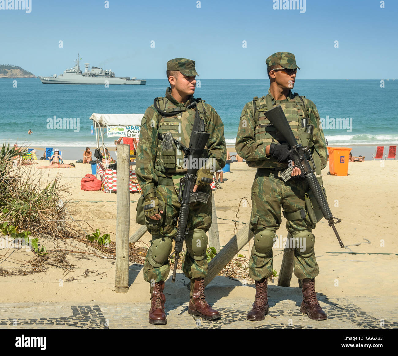 Il brasiliano della polizia militare guardare oltre i turisti e i locali presso la spiaggia di Ipanema a Rio de Janeiro durante il Rio 2016 Foto Stock