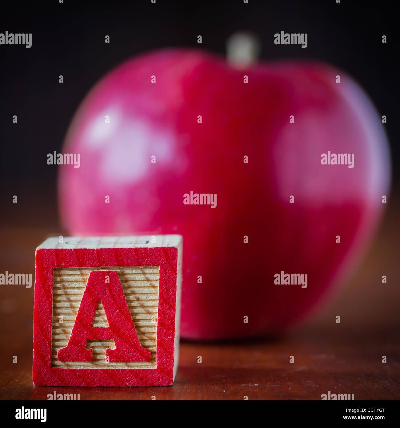 Un bambino di blocco di legno con la lettera A e un apple defocalizzata in background. Foto Stock