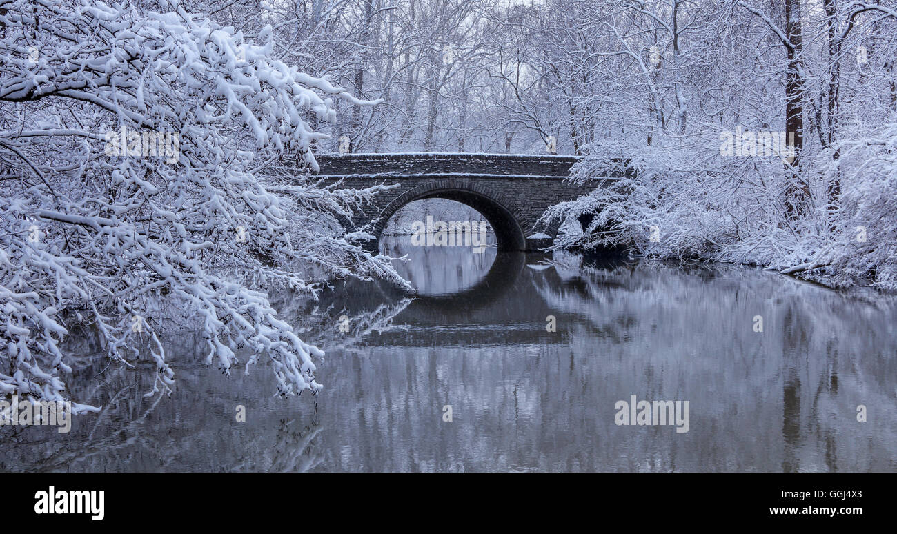Coperta di neve alberi e il ponte di pietra si riflette nel fiume di acqua durante l'Inverno nel parco, Sharon boschi, Southwestern Ohio, Stati Uniti d'America Foto Stock