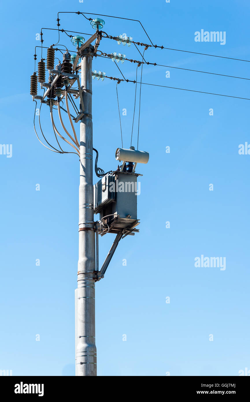 Trasformatore elettrico al pilone elettrico contro il cielo blu Foto Stock