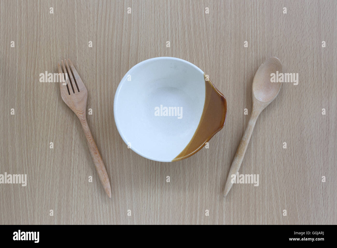 Cucchiaio di legno,forcella e piatto in vista dall'alto su uno sfondo di legno per il design concept food. Foto Stock