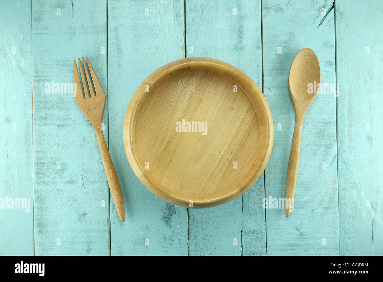 Il cucchiaio di legno e la forcella disposta vicino al vaso su un legno verde sfondo per i concetti di progettazione in health food. Foto Stock