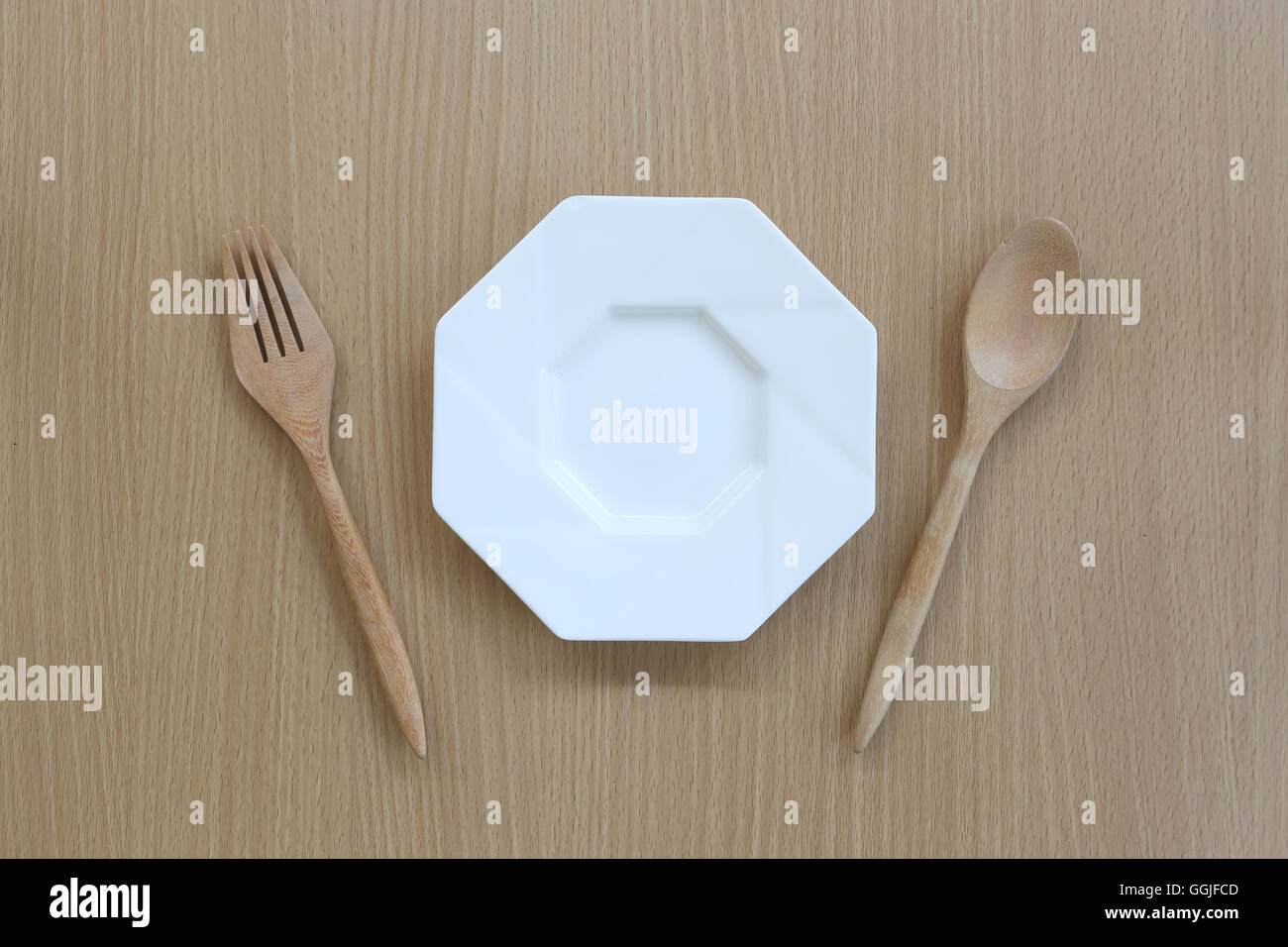 Cucchiaio di legno,forcella e piatto in vista dall'alto su uno sfondo di legno per il design concept food. Foto Stock