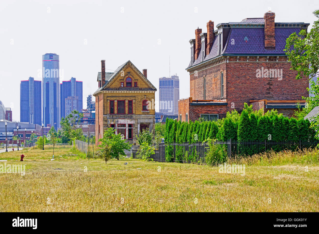 Detroit spazzola del parco della rimanente case vittoriane e lotti vacanti con downtown Renaissance Center in distanza. Foto Stock