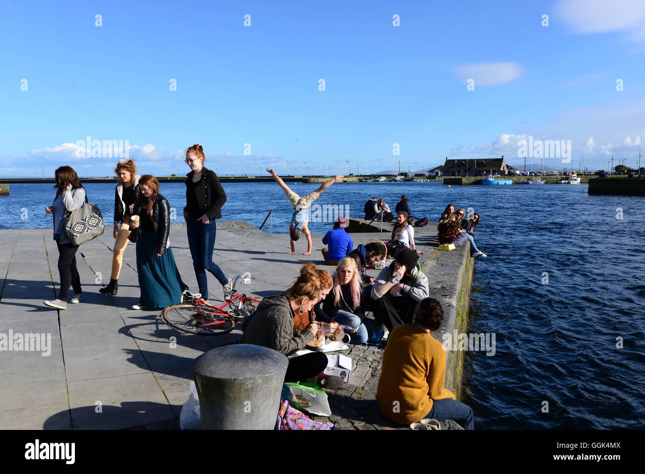I giovani seduti sulle rive del fiume Corrib, Galway, Irlanda Foto Stock