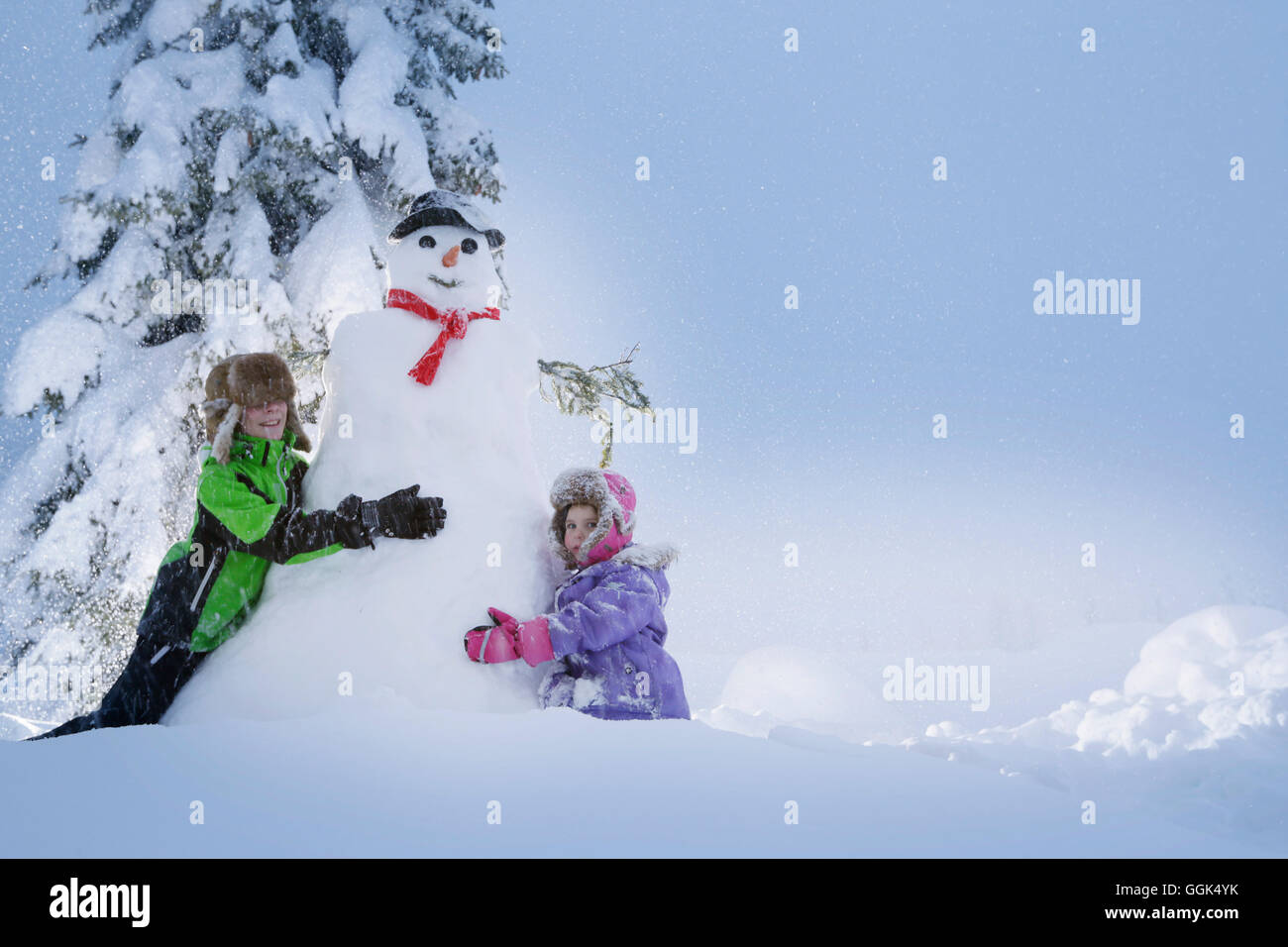 I bambini intenti a costruire un pupazzo di neve, Passo Monte Croce di Comelico, Alto Adige, Italia Foto Stock