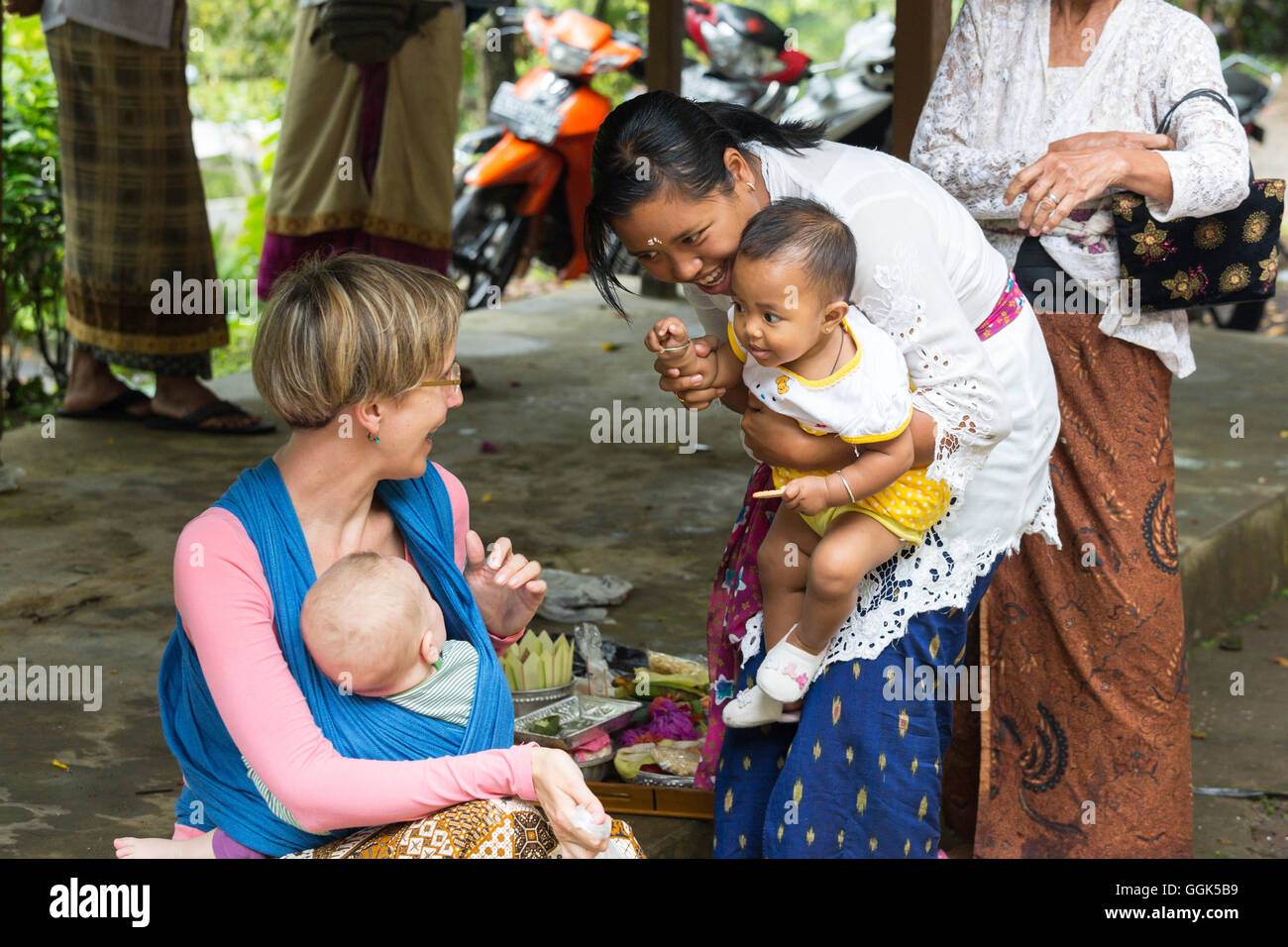 Madre Balinese con i suoi bambini a giocare con il Bambino di madre tedesca, baby sling, wrap, baby sling a sua madre, il bambino di 5 mesi Foto Stock