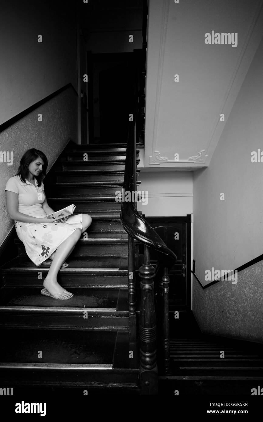 Una giovane donna seduta sulla scala di un edificio e la lettura di un libro (foto in bianco e nero), Berlino, Germania, Europa Foto Stock