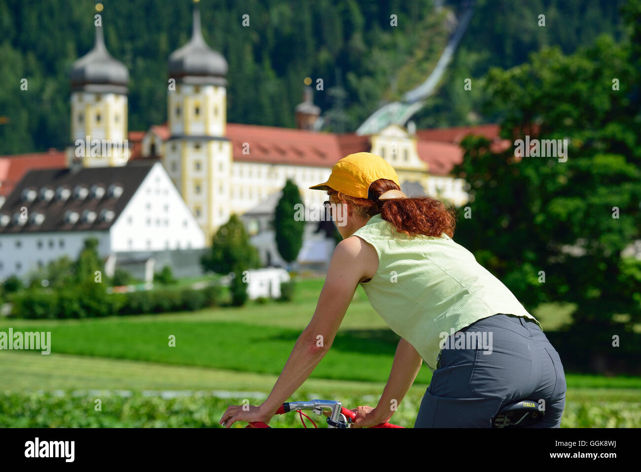 Donna ciclismo, monastero Stams in background, Stams, Tirolo, Austria Foto Stock