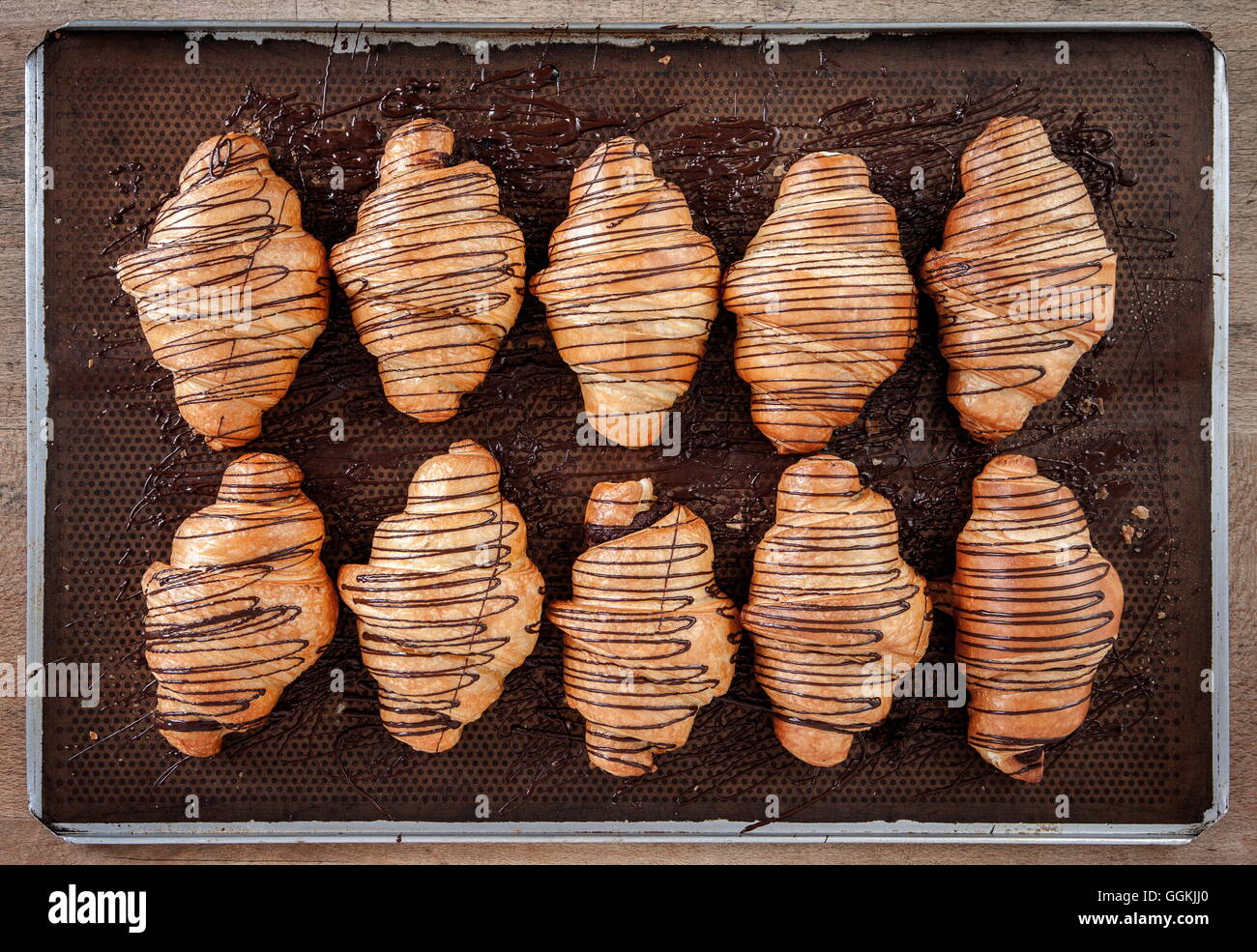 Cornetto al forno con cioccolato collocato su marrone carta cerata in un vassoio di acciaio inossidabile Foto Stock