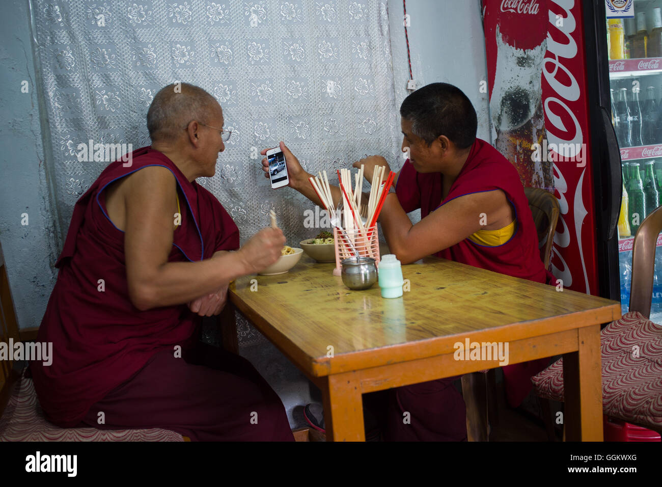 Due monaci buddisti guardando un modello di auto sullo schermo di un telefono in un ristorante di Dharamsala, in India. © Jordi Boixareu Foto Stock