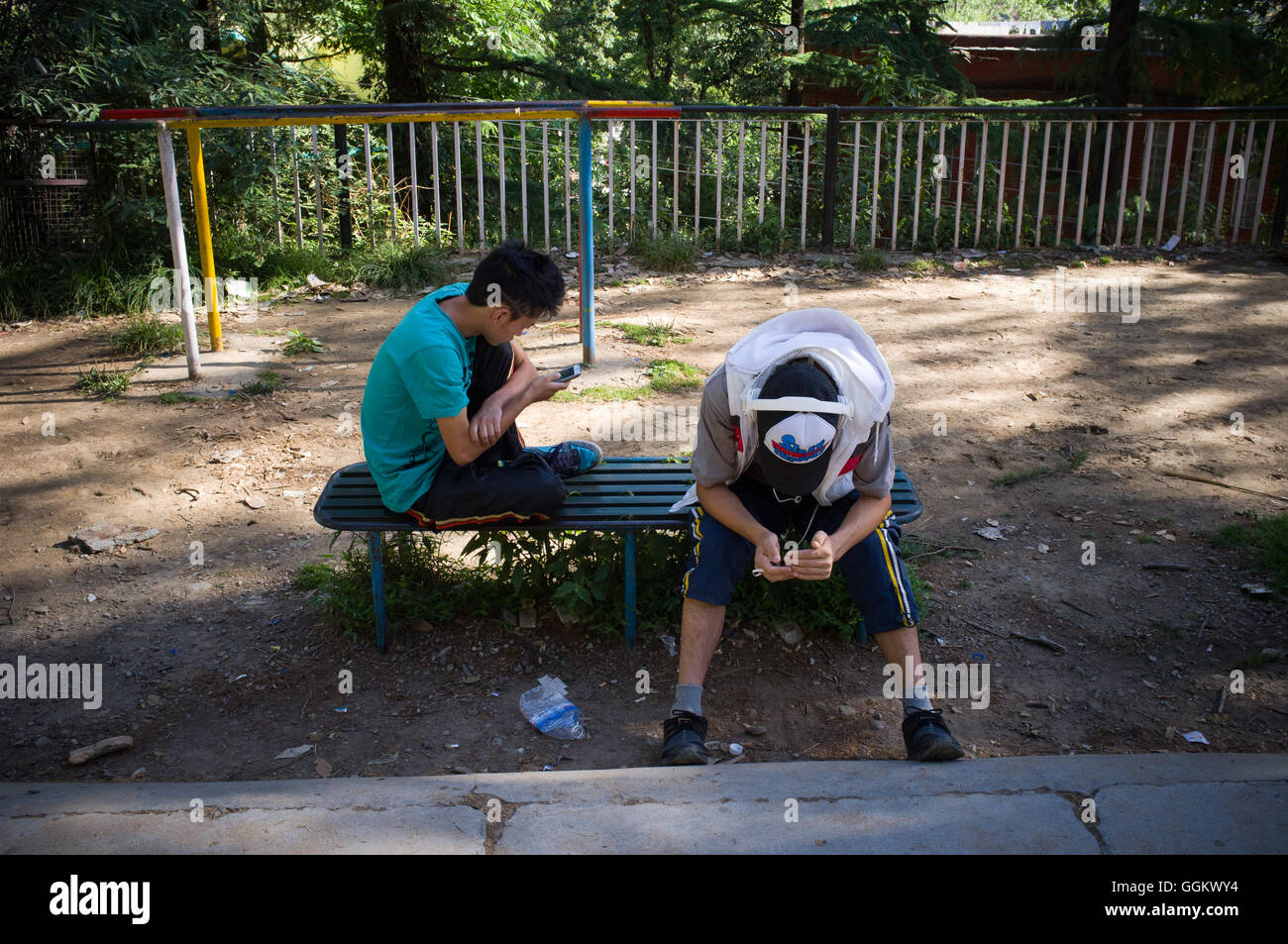 Due giovani uomini verificare si tratta di telefoni in un parco di Mcleod Ganj Dharamsala, Himachal Pradesh, India. © Jordi Boixareu Foto Stock