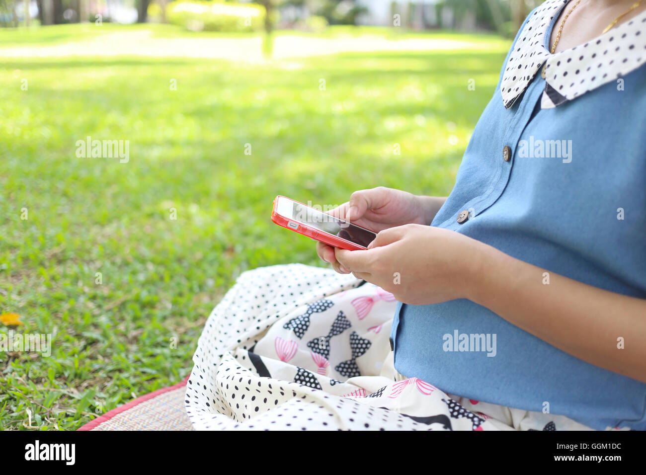 Donne in stato di gravidanza utilizzando gli smartphone a cercare informazioni sulle cure sanitarie nel parco pubblico. Foto Stock