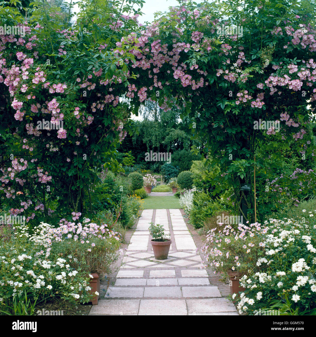 Giardino estivo - con Rosa "Apple Blossom" sopra l'arco e il percorso che conduce l'occhio alla vista oltre - RIVISTA FRANCESE DIRITTI NON Foto Stock