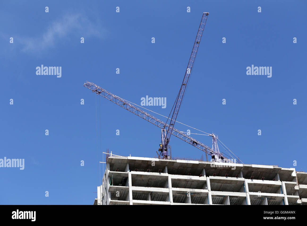 Gru lavorando su un edificio in costruzione in day time e cielo blu sullo sfondo. Foto Stock