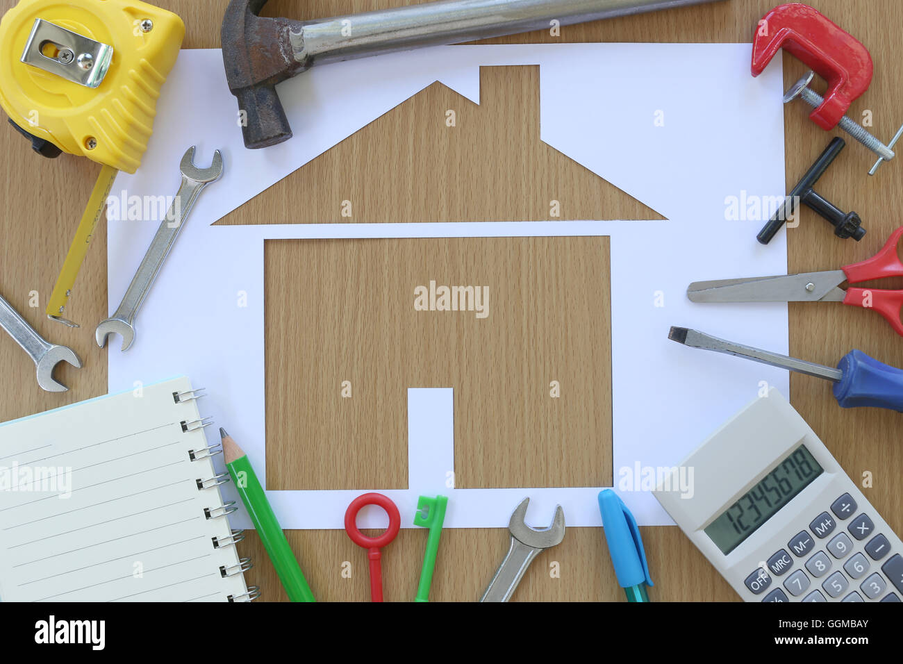 Carta casa sagomata su uno sfondo di legno marrone e artigiano attrezzo,idee per il concetto di design dell'edificio aziendale. Foto Stock