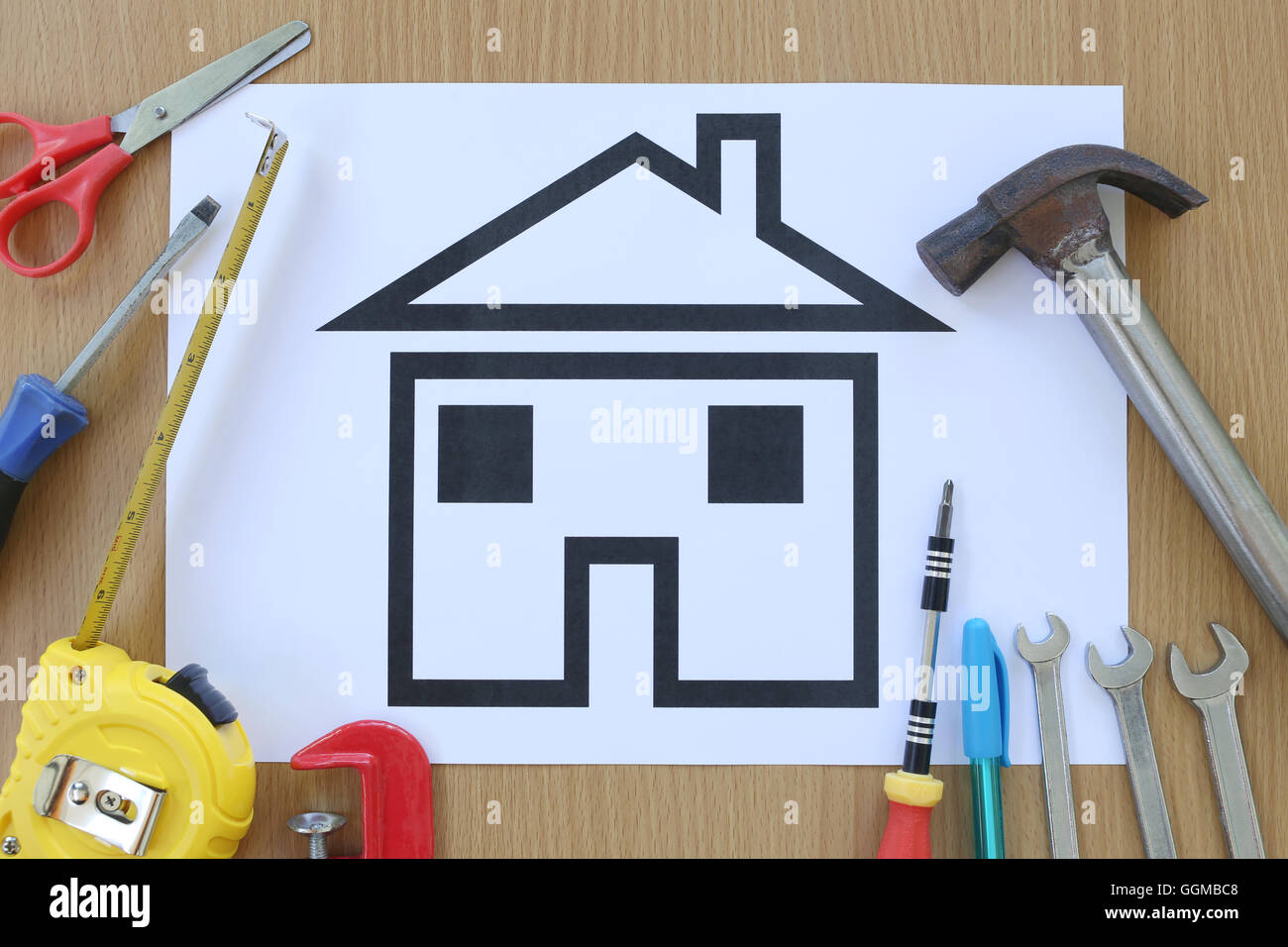 Carta casa sagomata su uno sfondo di legno marrone e artigiano attrezzo,idee per il concetto di design dell'edificio aziendale. Foto Stock