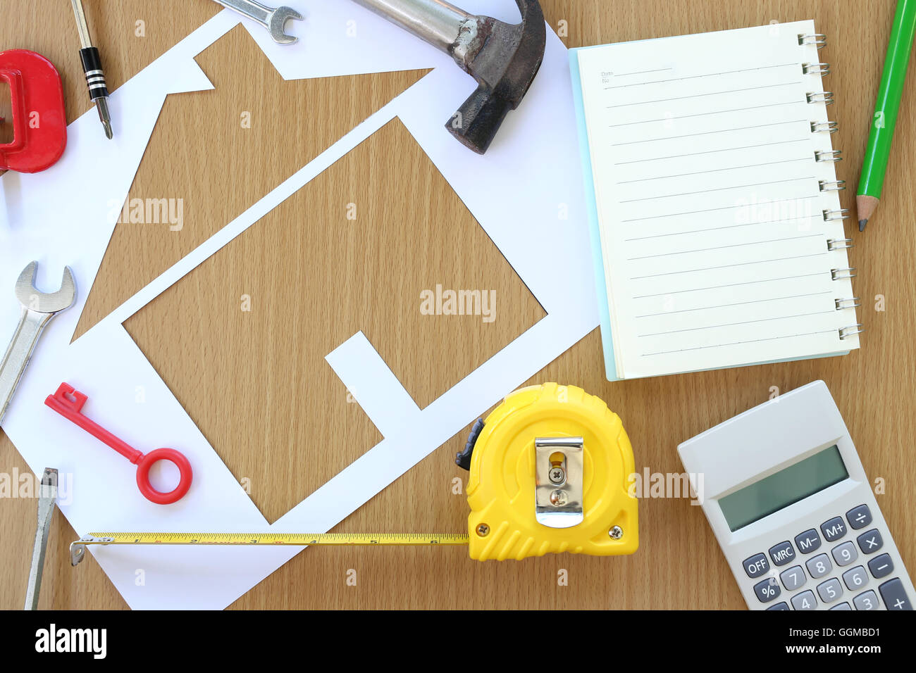 Carta casa sagomata su uno sfondo di legno marrone e artigiano attrezzo,idee per il concetto di design dell'edificio aziendale. Foto Stock