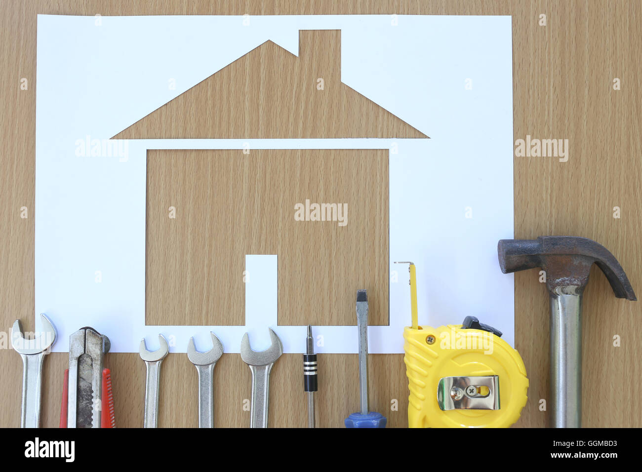 Carta casa sagomata su uno sfondo di legno marrone e artigiano attrezzo,idee per il concetto di design dell'edificio aziendale. Foto Stock