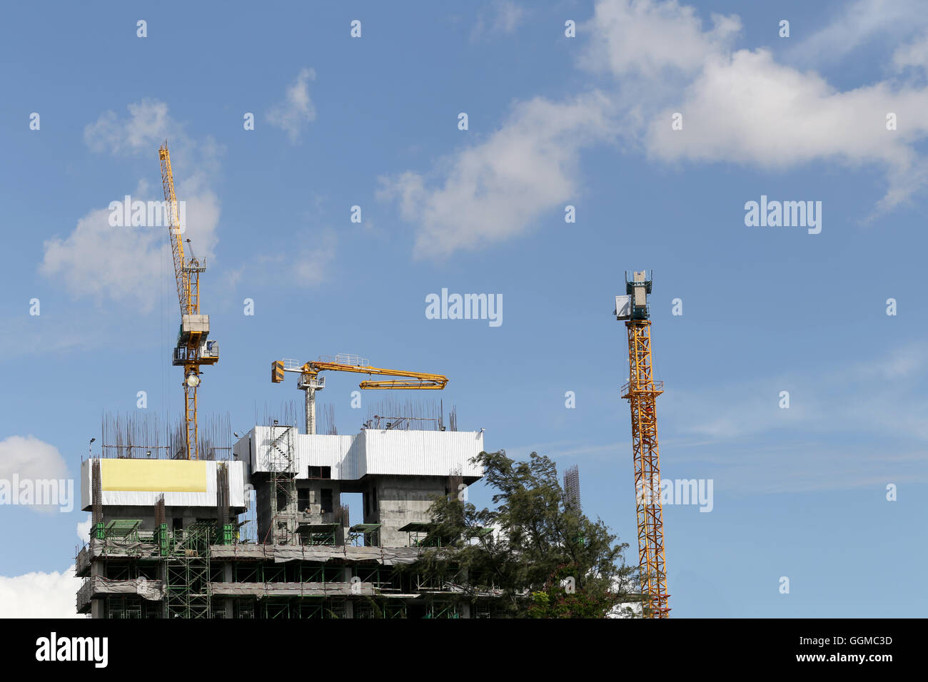 Gru lavorando su un edificio in costruzione in day time e cielo blu sullo sfondo. Foto Stock