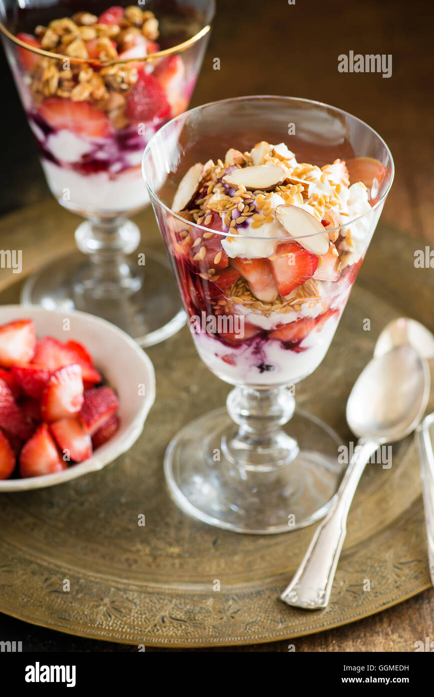 Yogurt con fragole, noci e semi di lino in vetro sul vassoio vintage, il fuoco selettivo Foto Stock