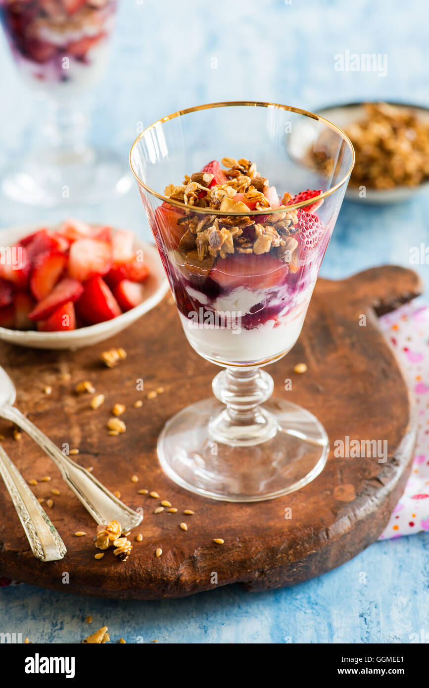 Yogurt con fragole, noci e semi di lino in vetro su tavola di legno, fuoco selettivo Foto Stock