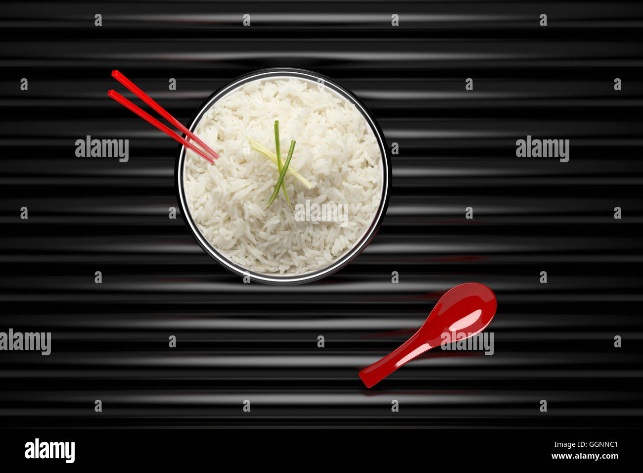 Bacchette in una ciotola di riso in bianco con cucchiaio rosso Foto Stock