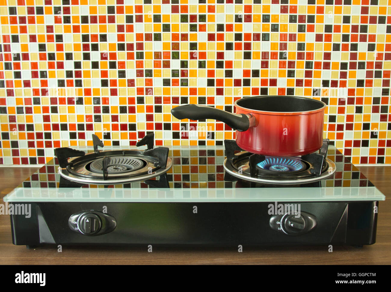 Recipiente rosso sul fornello a gas in camera con cucina. Foto Stock