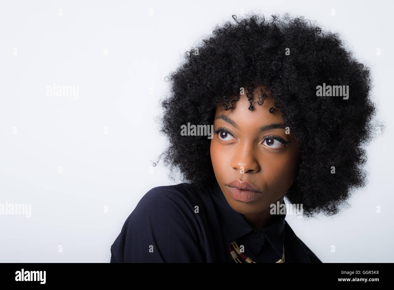 La giovane donna caraibica afro dei suoi 20 anni guarda in alto a sinistra della cornice con spazio di copia a sinistra dell'immagine Foto Stock