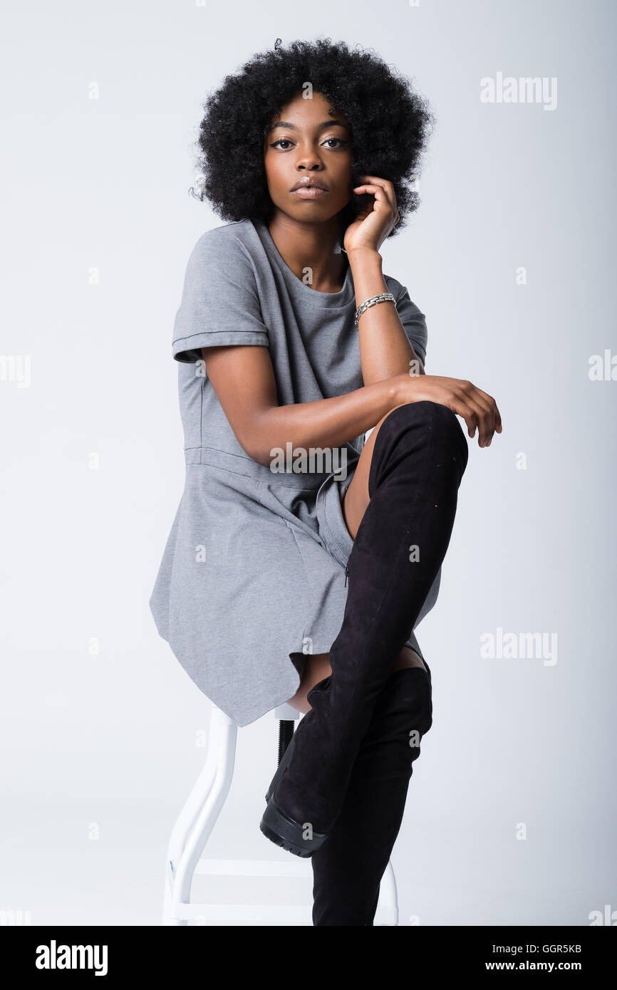 Una modella afro caraibica seduta sui 20 anni che scatta immagini di moda Foto Stock