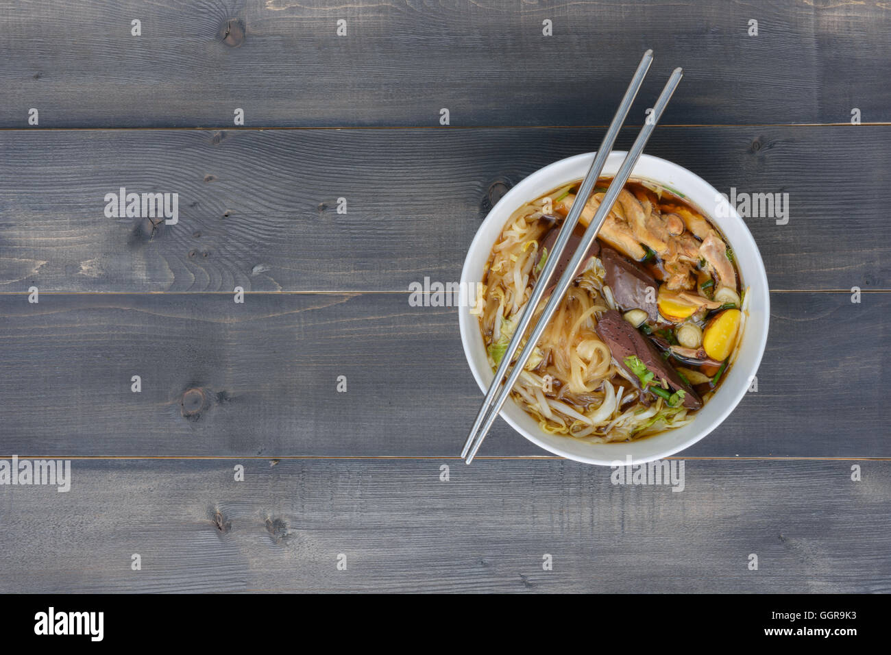 Zuppa di noodle con bacchette in ciotola su una tavola di legno, vista dall'alto, Tailandese cibo locale Foto Stock