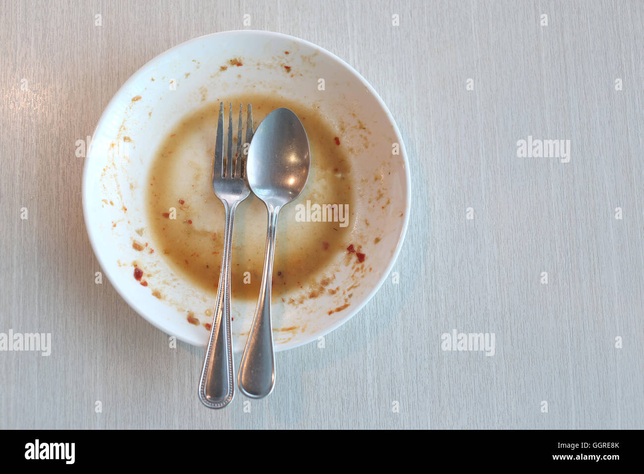 Piatto bianco sporco dopo aver messo un cibo e finito di mangiare sul tavolo del ristorante. Foto Stock
