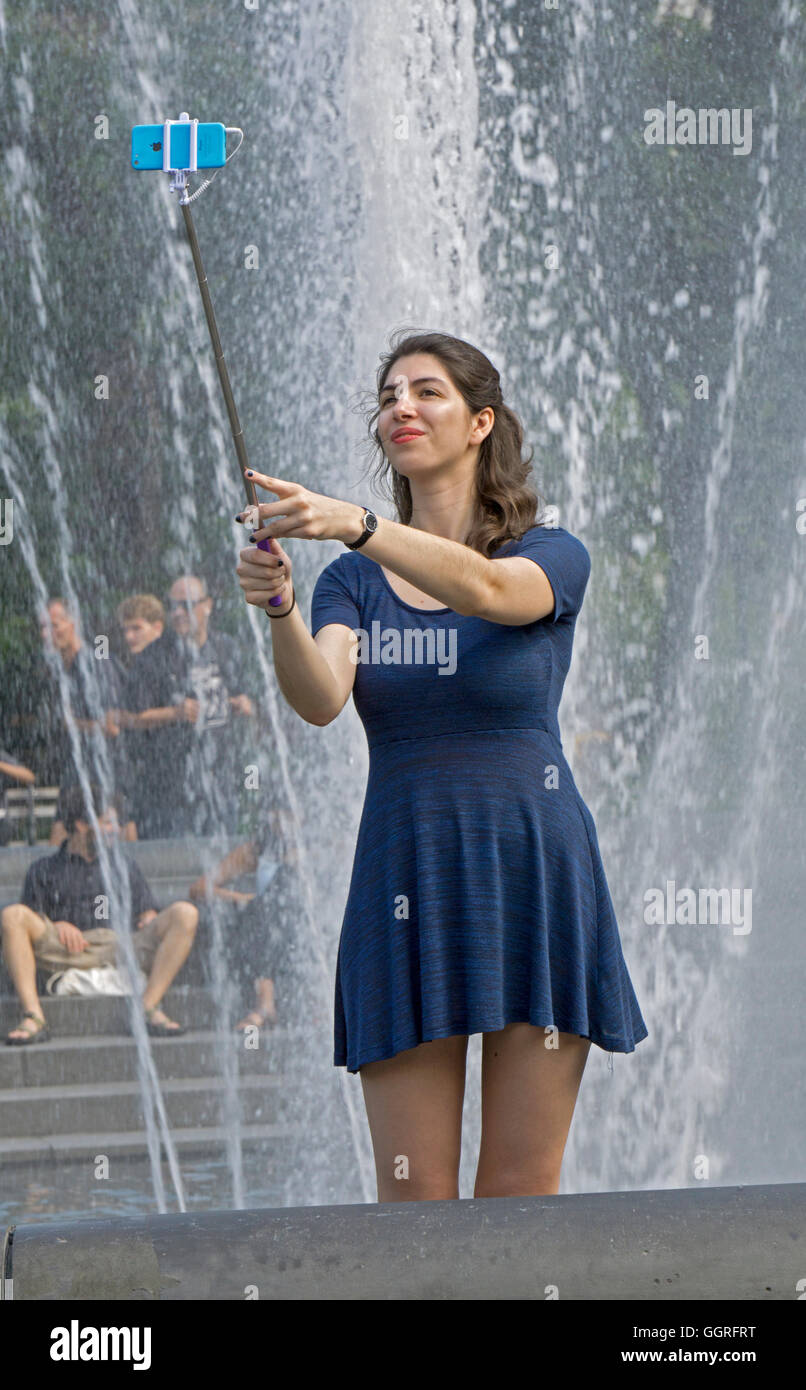 Una donna attraente in visita a New York prendendo un selfie presso la fontana di Washington Square Park in Greenwich Village. Foto Stock