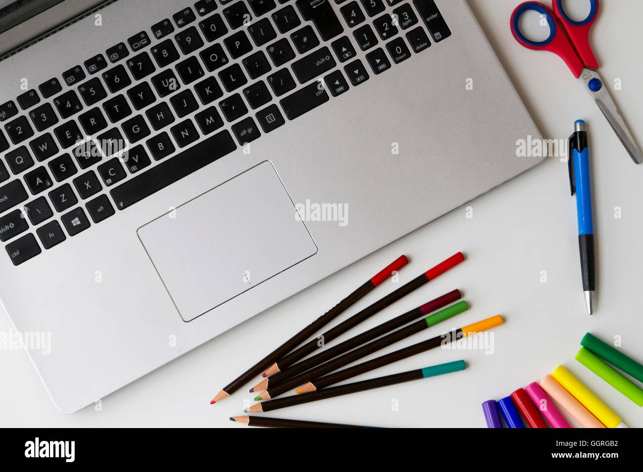 PC laptop e alcuni oggetti come penne, matite colorate, punta in feltro  penne, forbici sul tavolo bianco. Vista dall'alto. Lay piatto Foto stock -  Alamy
