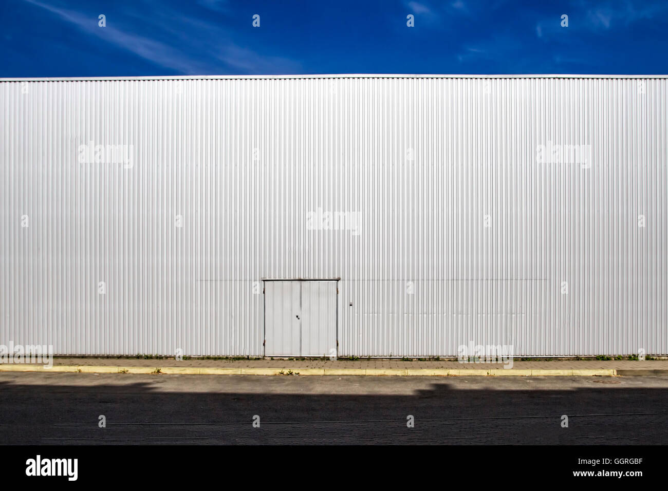 Lamiera grecata parete con una porta, la strada delle ombre e cielo blu.  All'esterno. Look industriale. Sfondo digitale per i fotografi Foto stock -  Alamy