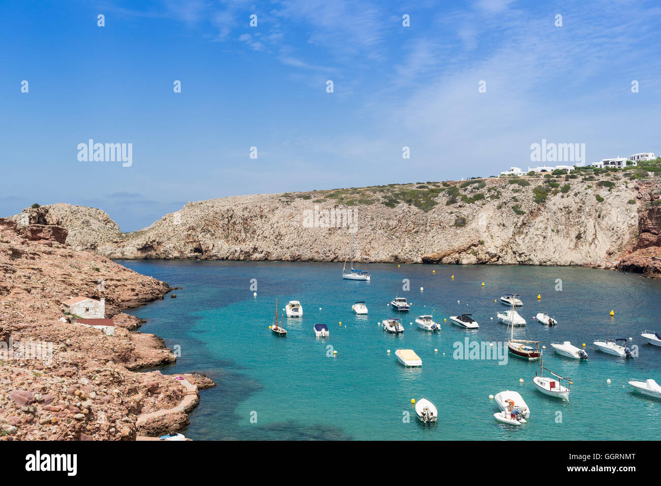 Barche in un blu turchese baia circondata da scogliere e rocce Foto Stock