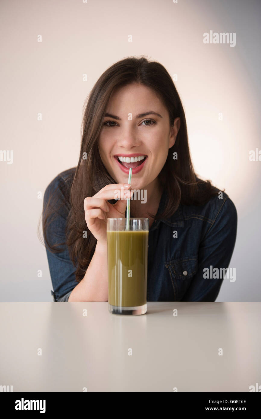 La donna caucasica bere frullato verde con paglia Foto Stock