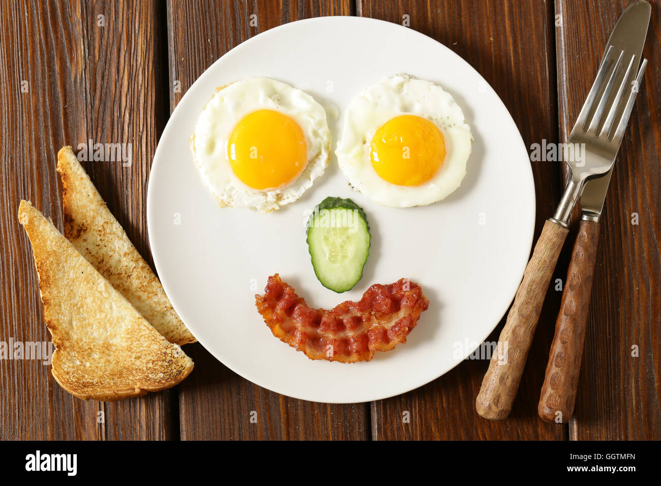 Faccia buffa che serve la prima colazione, uova fritte e toast Foto Stock