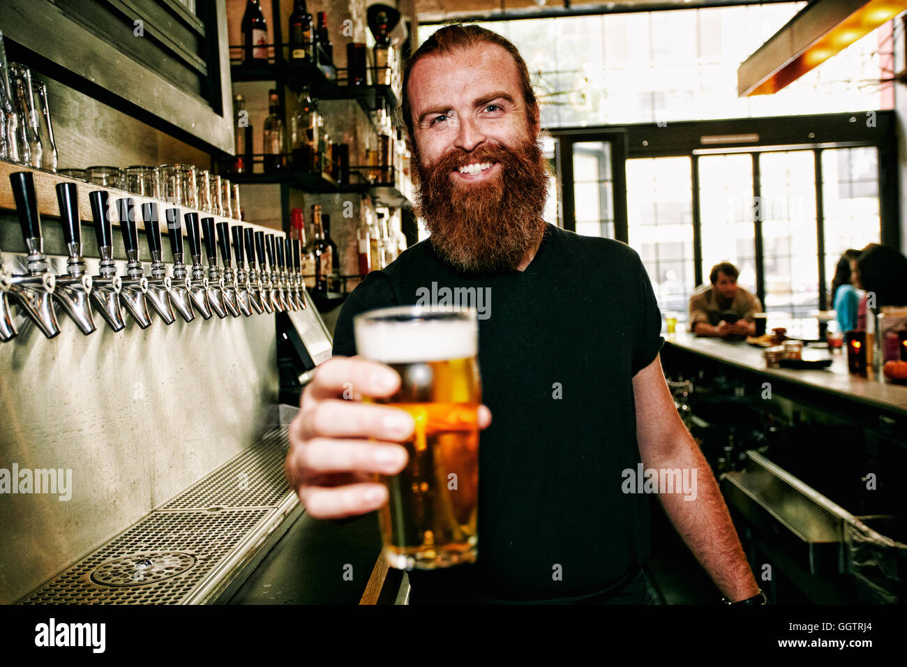 Sorridente Caucasian barista che serve birra al bar Foto Stock