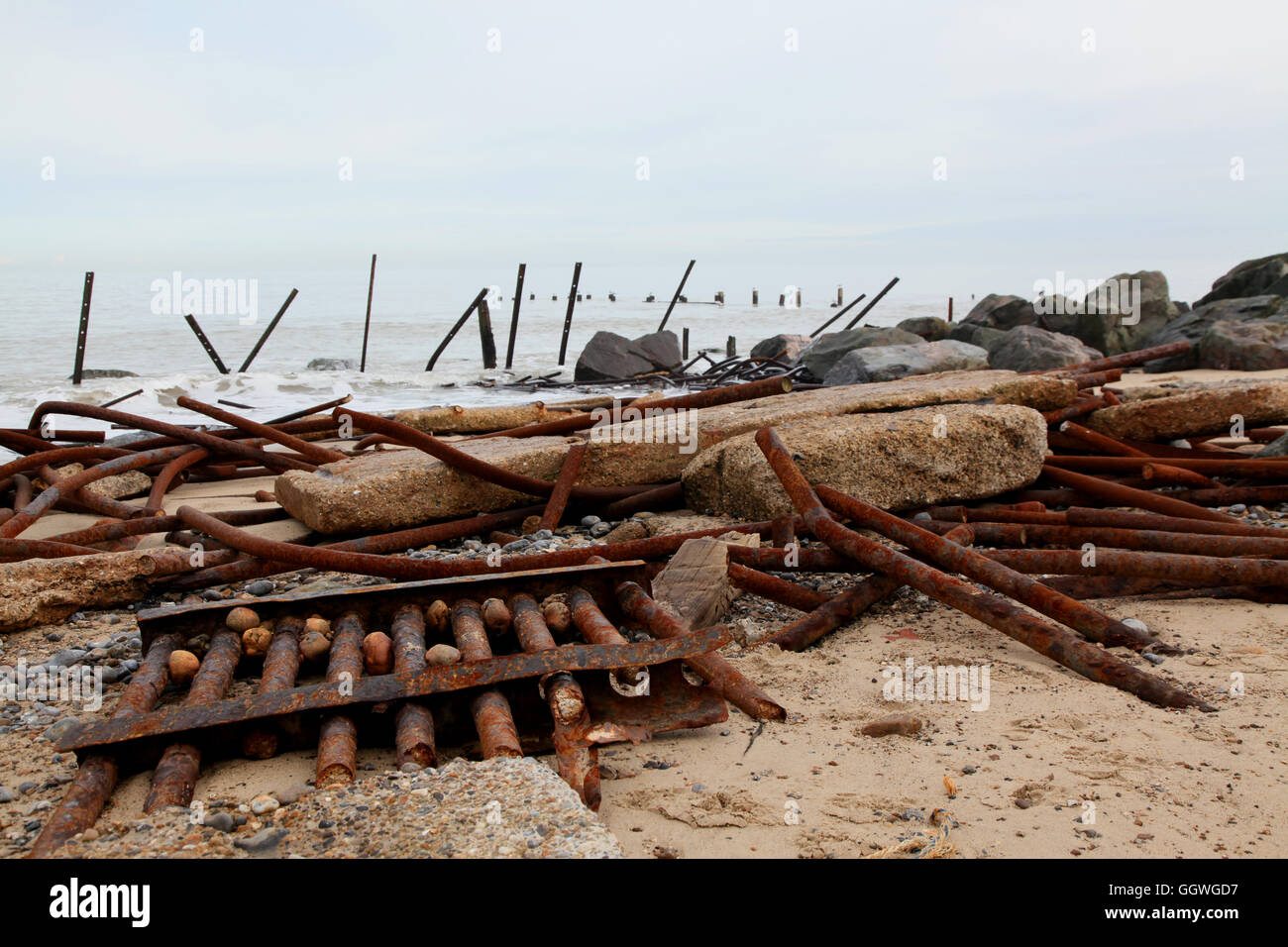 Barriere in acciaio e calcestruzzo lastre di forma le difese costiere che sono stati schiacciati dalla natura per permettere al mare di erodere la costa Foto Stock
