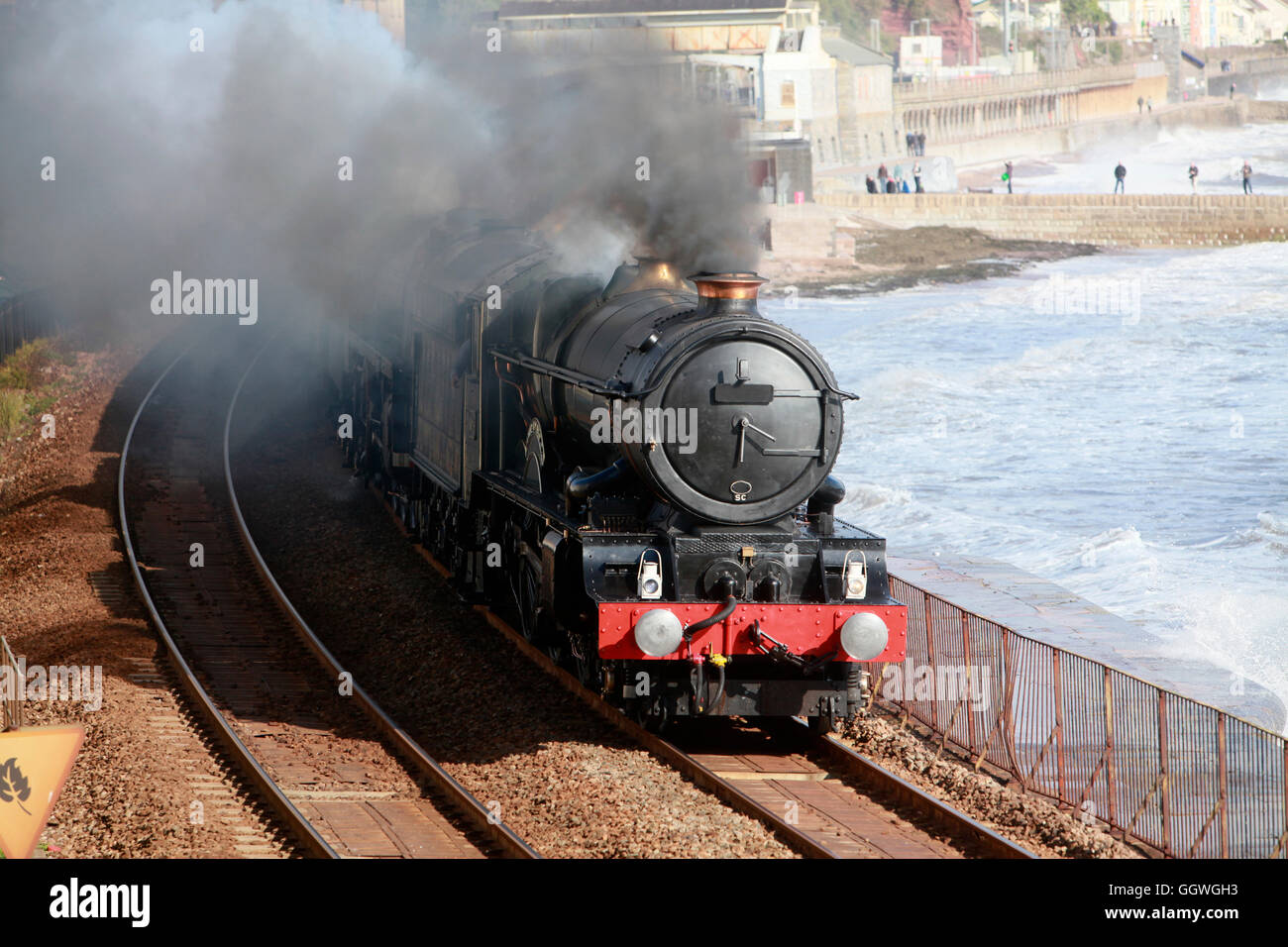 Un vintage locomotiva a vapore passa attraverso Dawlish sul famoso Brunel linea ferroviaria Foto Stock