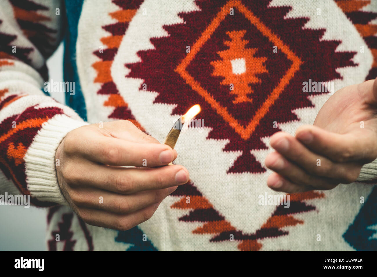 L'uomo mani tenendo fuoco corrisponde allo stile di vita di viaggio il concetto di sopravvivenza di indossare pullover a maglia per esterno Foto Stock