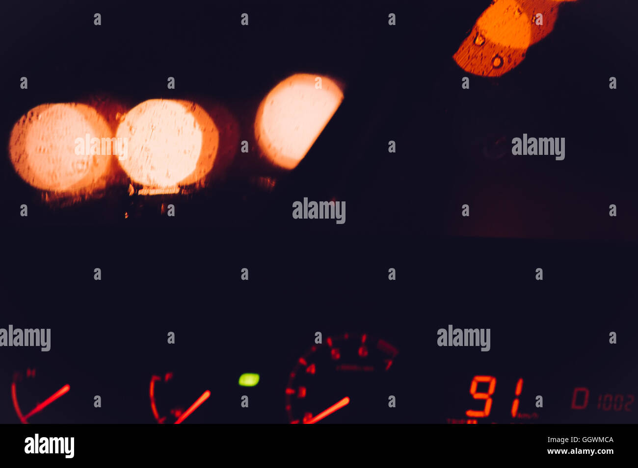 Notte via strada e fari di automobili con finestra piovosa e led pannello tachimetro sfondo sfocato concetto di viaggio Foto Stock