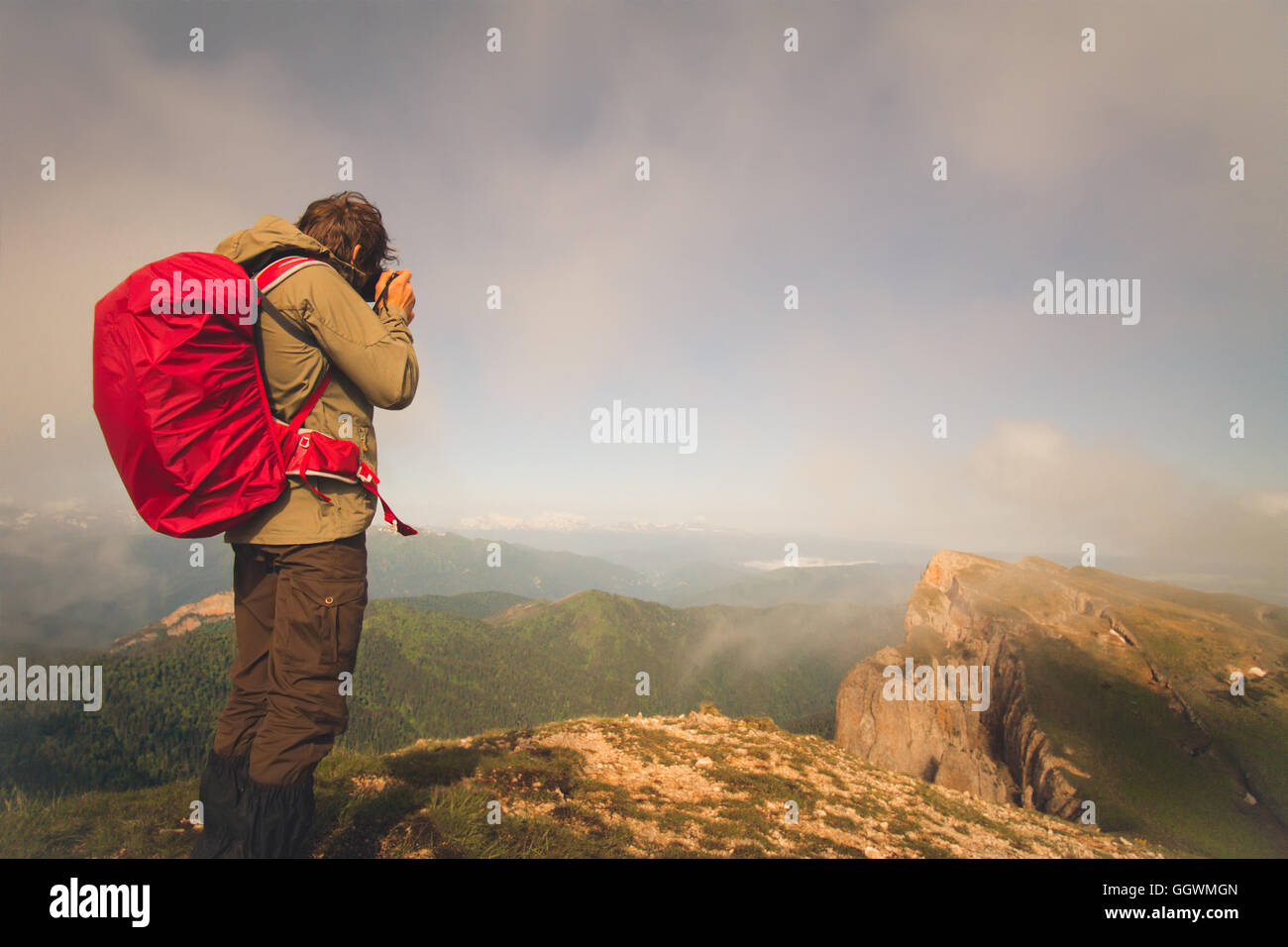 L'uomo viaggiatore con foto e fotocamera zaino escursionismo Outdoor Lifestyle viaggio concetto di sopravvivenza montagne nuvole sullo sfondo Foto Stock